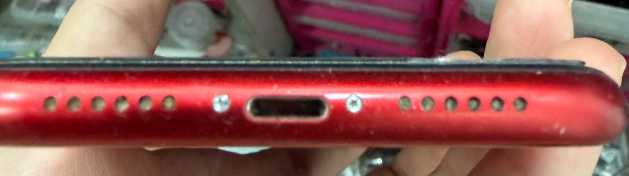 Conector de carga y rejillas inferiores de un iPhone antes de su revisión y limpieza
